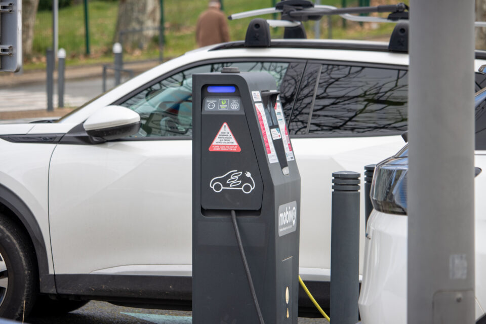 Voiture électrique branchée sur une borne de recharge avec un Disque vert sur le pare-brise